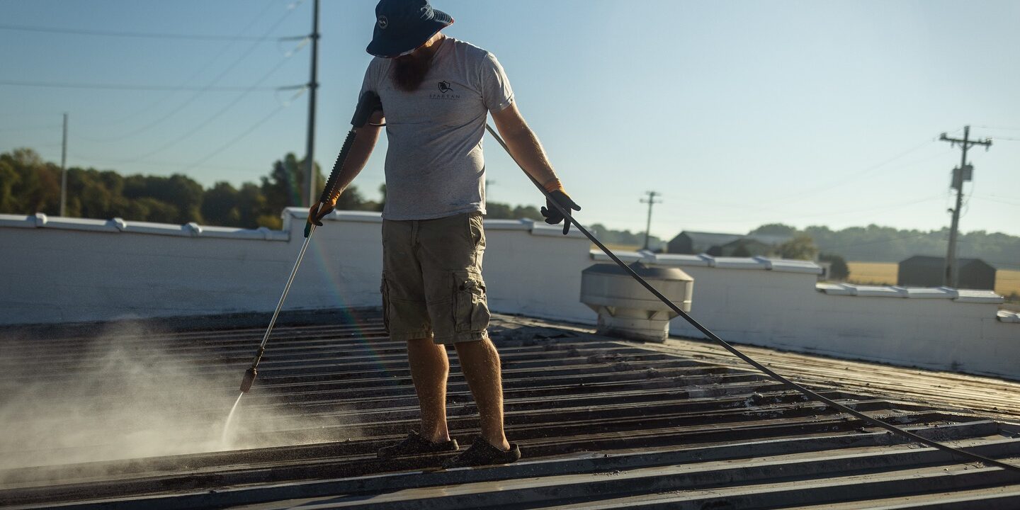 Man pressure washing a roof