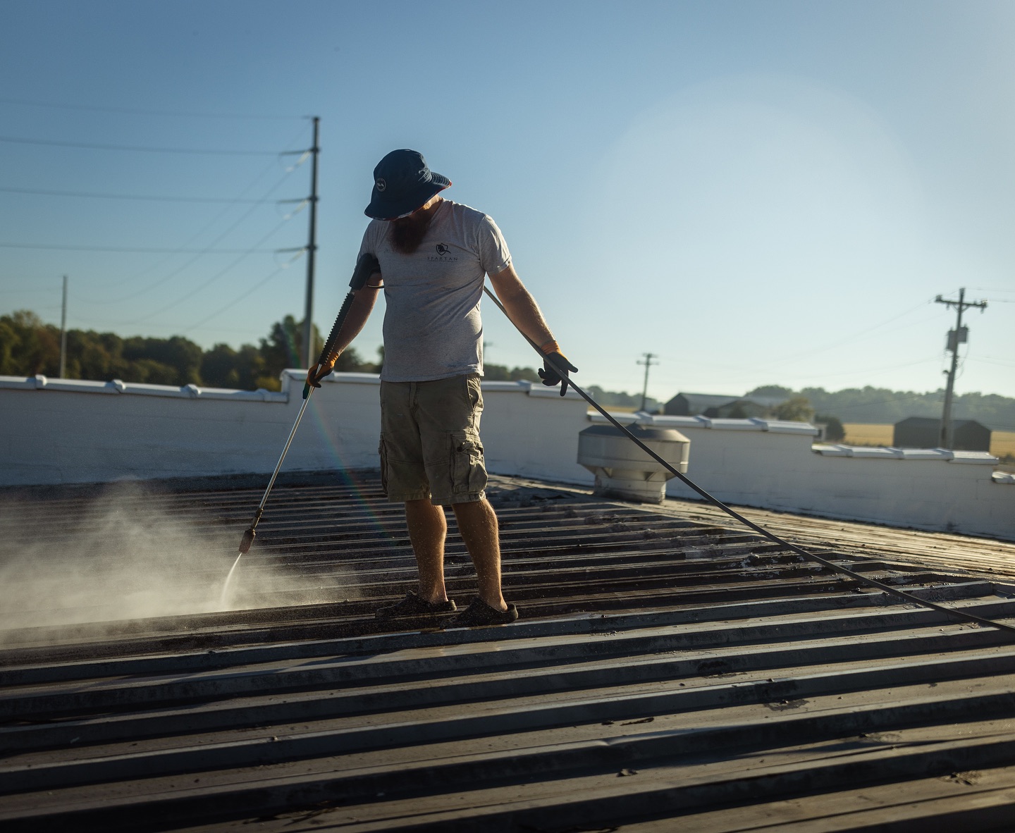 Man pressure washing a roof
