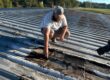 Man inspecting a roof and pointing at a damaged spot