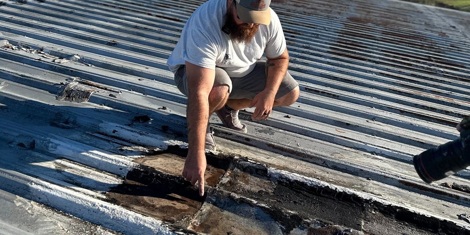 Man inspecting a roof and pointing at a damaged spot