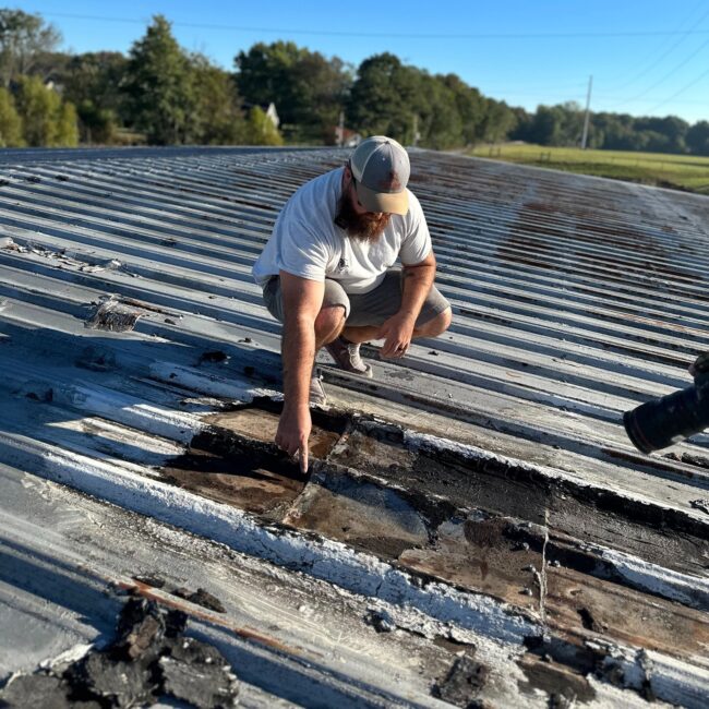 Man inspecting a roof and pointing at a damaged spot