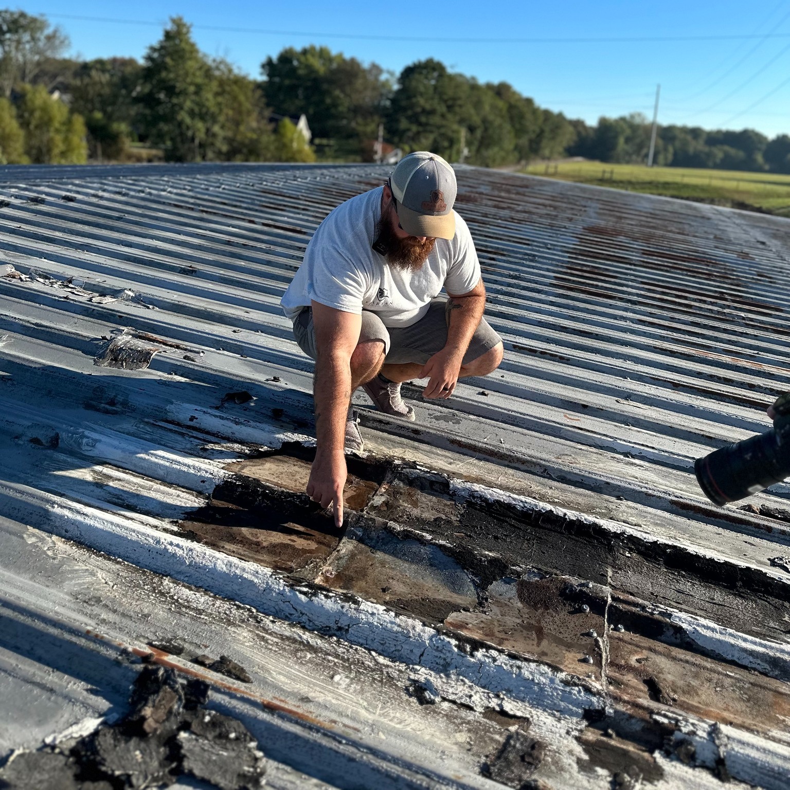 man inspecting a roof Man inspecting a roof and pointing at a damaged spot