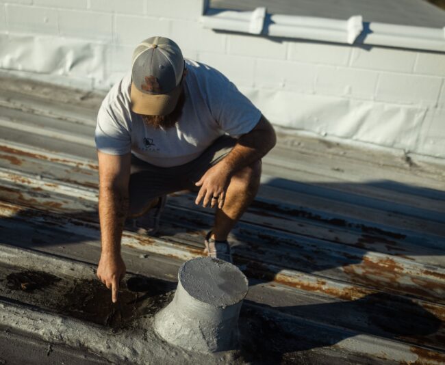 Man touching a worn roof.